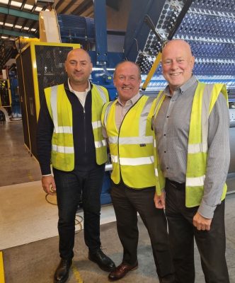 Three men in hi-vis in front of infinity machine in factory